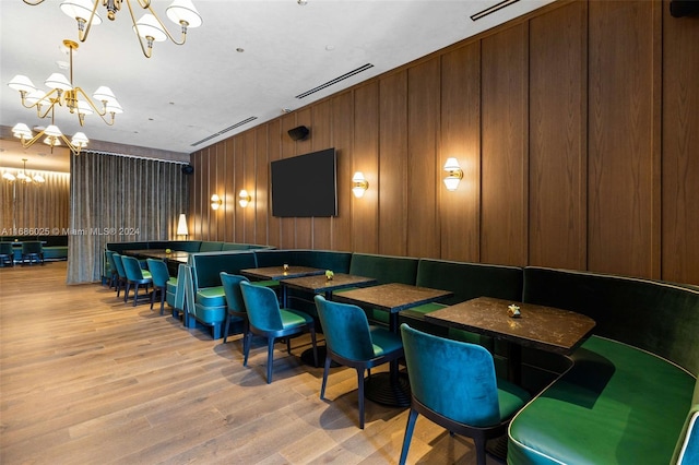 interior space featuring light hardwood / wood-style floors, a chandelier, and wooden walls