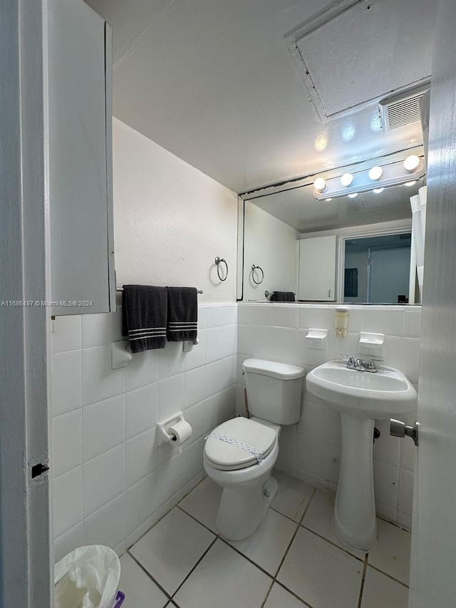 bathroom featuring tile patterned flooring, toilet, and tile walls