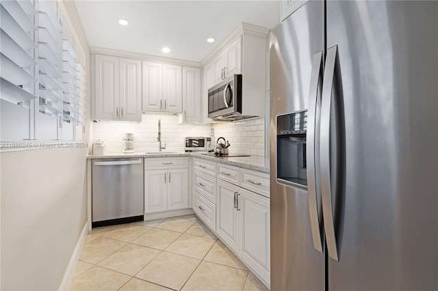 kitchen with light stone countertops, appliances with stainless steel finishes, white cabinetry, and light tile patterned floors