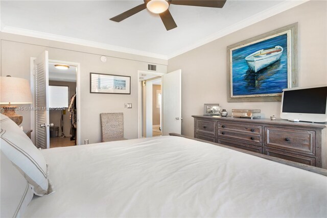 bedroom featuring a closet, ceiling fan, crown molding, and a walk in closet