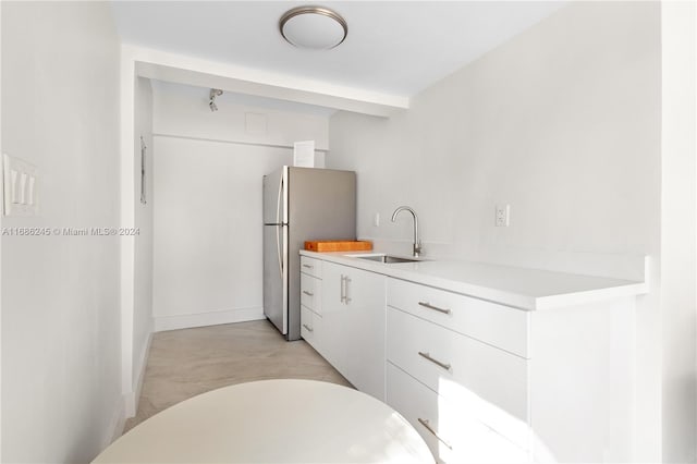 kitchen featuring stainless steel fridge, sink, and white cabinetry