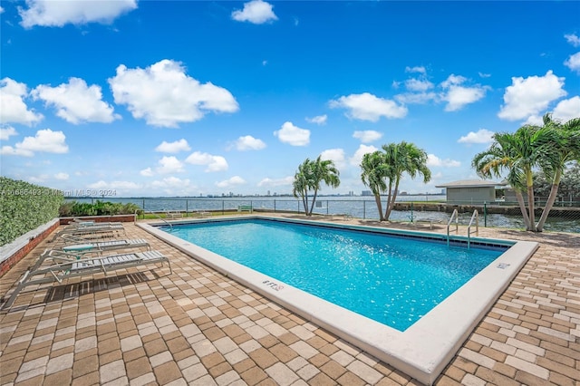 view of swimming pool featuring a water view and a patio