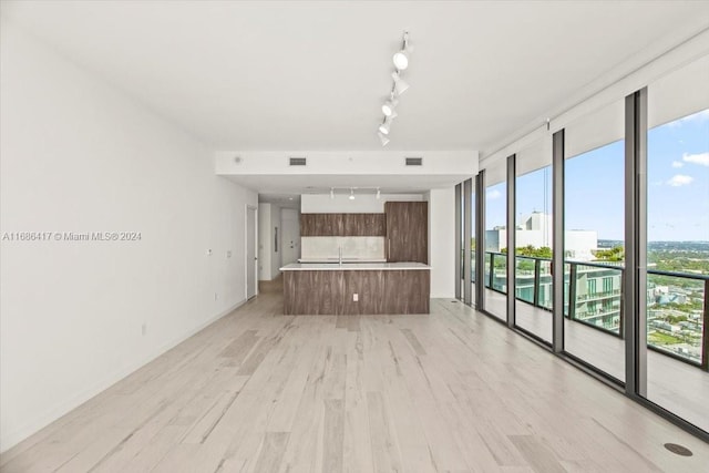 unfurnished living room featuring rail lighting and light wood-type flooring