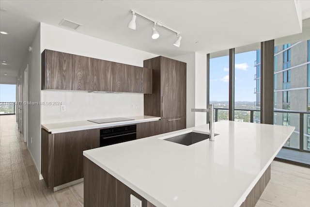 kitchen with a healthy amount of sunlight, black appliances, and a center island with sink