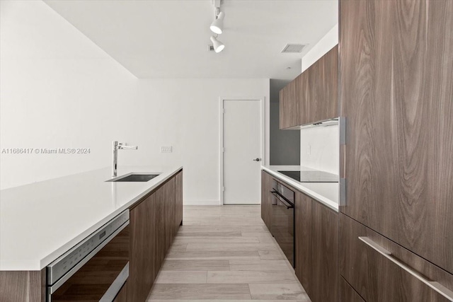 kitchen with light hardwood / wood-style floors, stainless steel appliances, track lighting, and sink