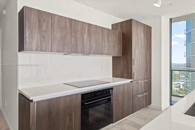 kitchen featuring black appliances, light hardwood / wood-style flooring, and backsplash