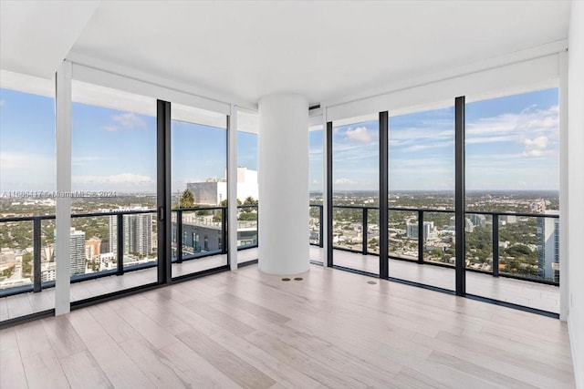 unfurnished room featuring a wall of windows and light hardwood / wood-style flooring