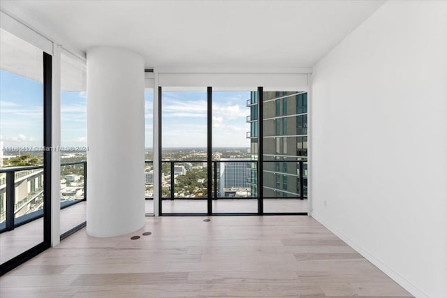 empty room with floor to ceiling windows and light wood-type flooring