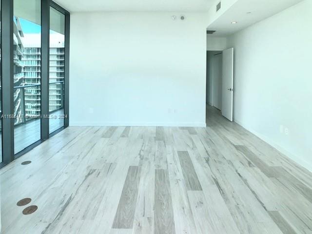 spare room with light hardwood / wood-style flooring and floor to ceiling windows