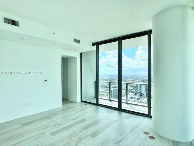 empty room with expansive windows and light wood-type flooring