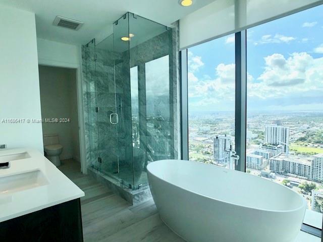 full bathroom featuring vanity, toilet, shower with separate bathtub, and hardwood / wood-style floors