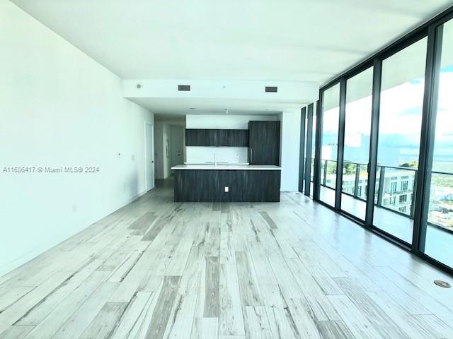 unfurnished living room with expansive windows, light hardwood / wood-style floors, and plenty of natural light