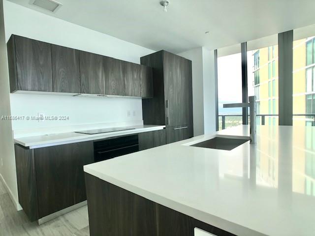 kitchen featuring light hardwood / wood-style floors, dark brown cabinets, a center island, and black electric cooktop