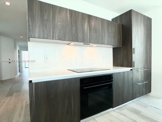 kitchen featuring light hardwood / wood-style floors, black appliances, and dark brown cabinets