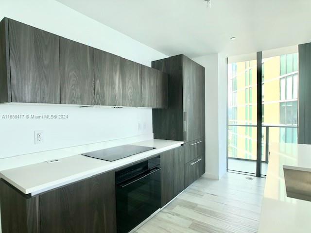 kitchen featuring light hardwood / wood-style floors, black appliances, and dark brown cabinets