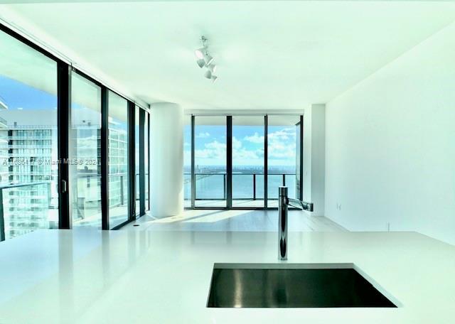 spare room with sink, rail lighting, and floor to ceiling windows