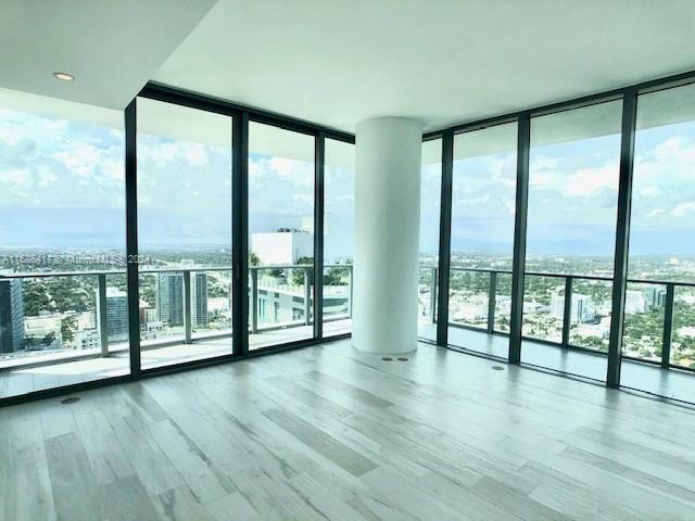 empty room with expansive windows, hardwood / wood-style floors, and a healthy amount of sunlight