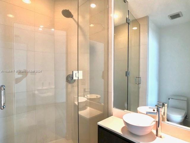 bathroom featuring vanity, toilet, and an enclosed shower