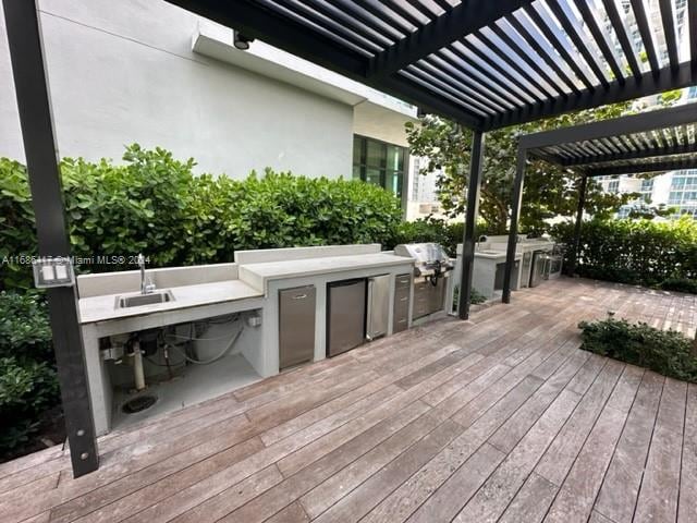 deck with a pergola, an outdoor kitchen, and a grill