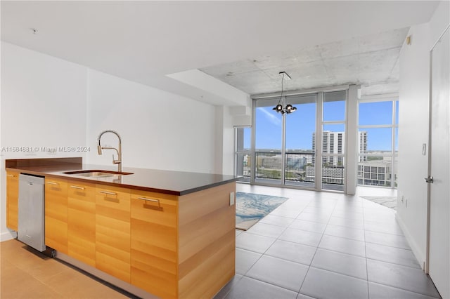 kitchen featuring sink, dishwasher, expansive windows, pendant lighting, and a notable chandelier