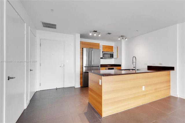 kitchen with dark tile patterned floors, sink, kitchen peninsula, and stainless steel appliances