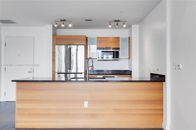 kitchen with tile patterned floors, appliances with stainless steel finishes, sink, and kitchen peninsula