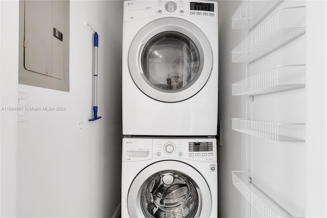 washroom featuring electric panel and stacked washer / dryer