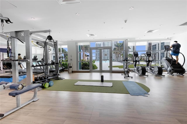 gym with light hardwood / wood-style floors and a wall of windows