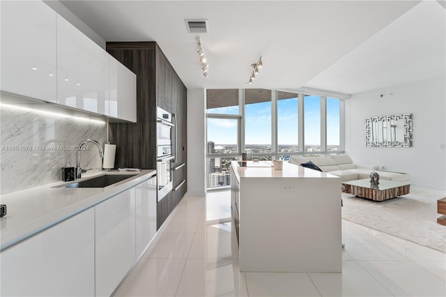 kitchen with decorative backsplash, white cabinets, sink, and rail lighting