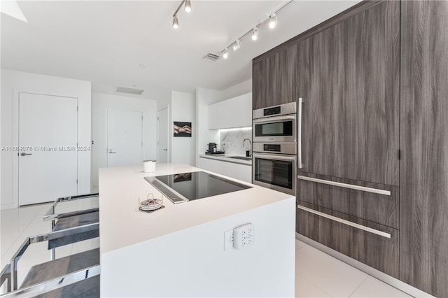 kitchen featuring a kitchen island, double oven, black electric cooktop, backsplash, and white cabinets