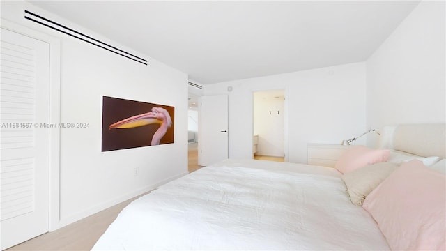 bedroom with ensuite bath and light hardwood / wood-style floors