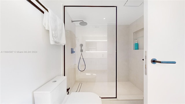 bathroom featuring tiled shower and toilet