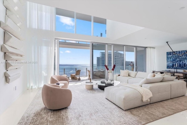 living area with a water view, a view of city, and a towering ceiling