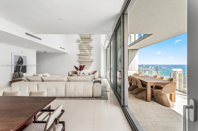 living area with a water view, visible vents, and floor to ceiling windows