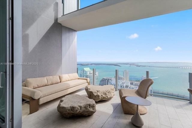 balcony featuring a water view, an outdoor living space, and a city view