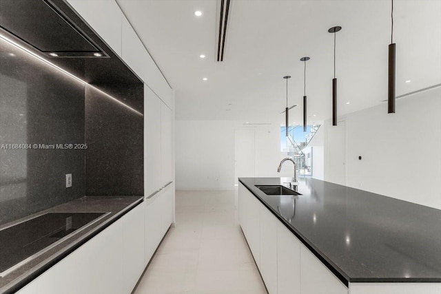 kitchen with a sink, white cabinetry, dark countertops, modern cabinets, and decorative light fixtures