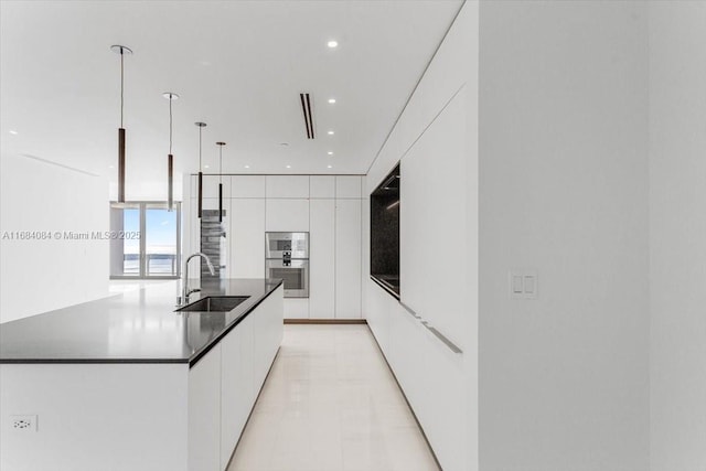 kitchen featuring a sink, white cabinetry, dark countertops, modern cabinets, and a large island with sink