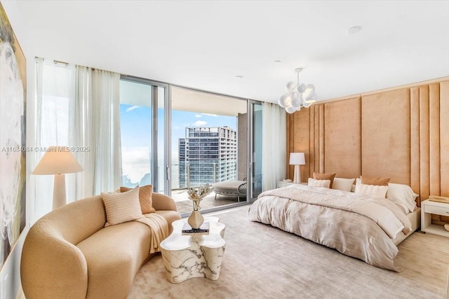 bedroom featuring access to exterior, a city view, an inviting chandelier, and a wall of windows