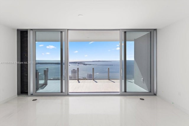 unfurnished room featuring a water view and baseboards