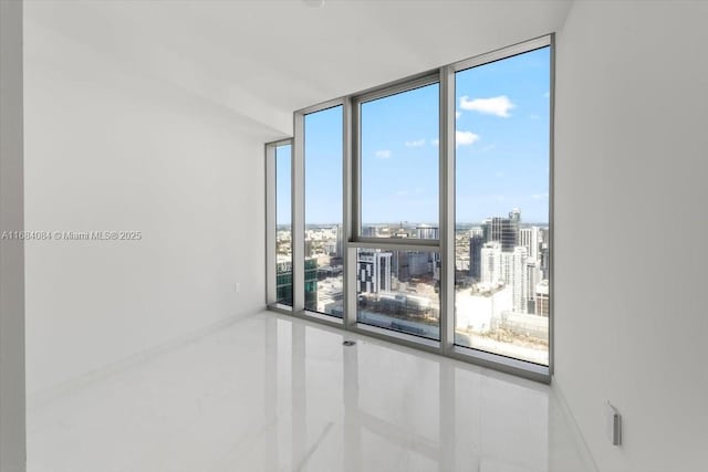 unfurnished room with a view of city, baseboards, and floor to ceiling windows