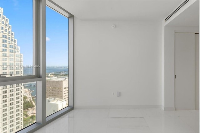 spare room featuring baseboards, floor to ceiling windows, and a city view