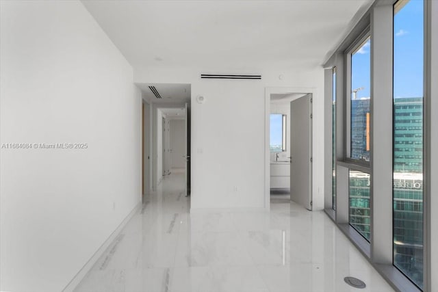 hall with marble finish floor, visible vents, a view of city, and baseboards