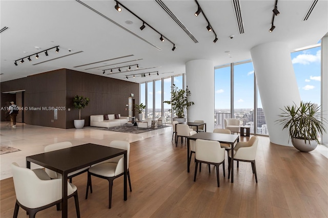 dining area featuring a wall of windows, light wood-type flooring, and rail lighting