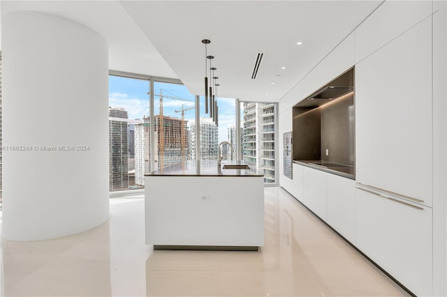 kitchen featuring white cabinets, plenty of natural light, a wall of windows, and hanging light fixtures