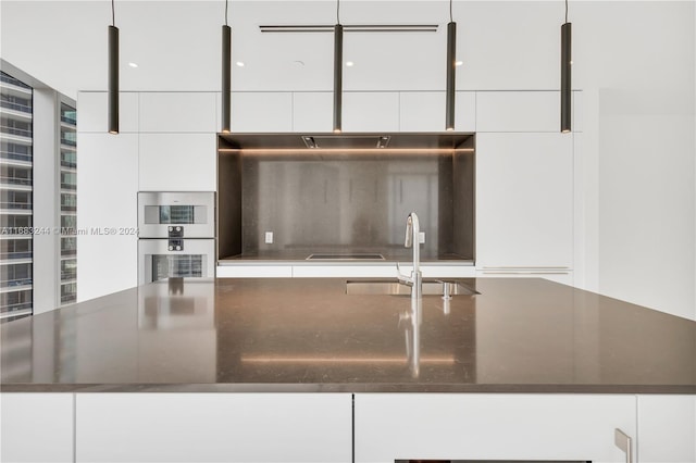 kitchen with sink, white cabinets, decorative backsplash, and stainless steel double oven