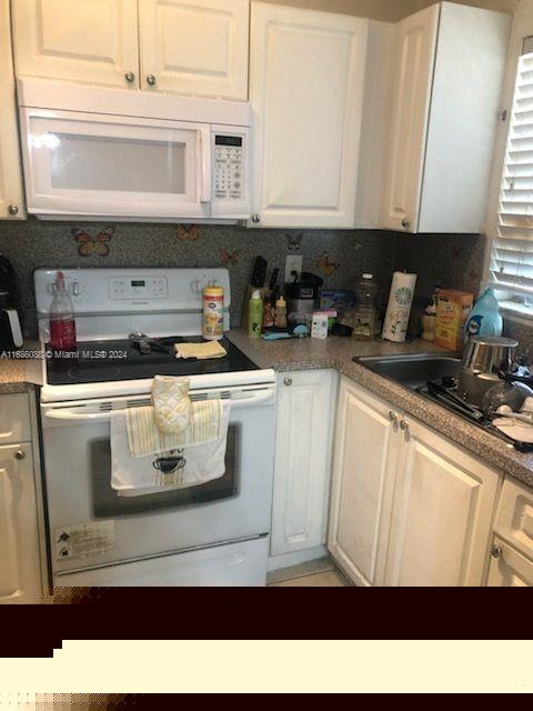 kitchen featuring backsplash, white appliances, sink, and white cabinets