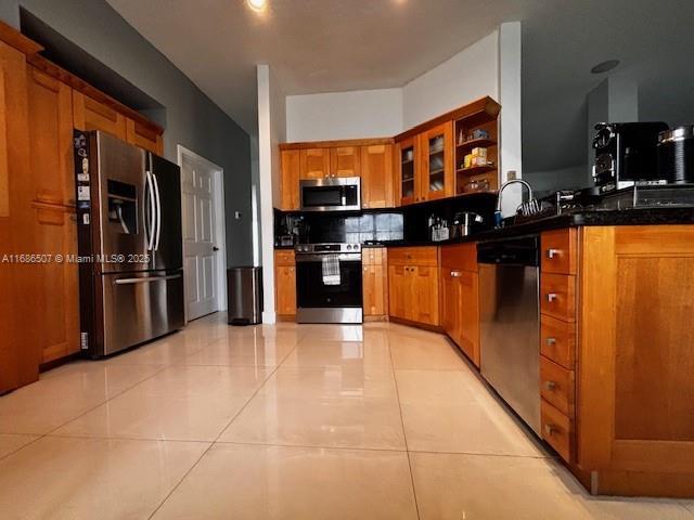 kitchen featuring kitchen peninsula, sink, light tile patterned floors, and appliances with stainless steel finishes