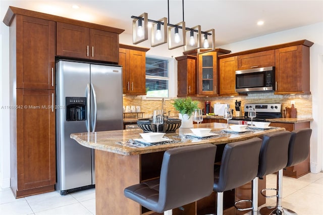 kitchen featuring a kitchen bar, a center island, appliances with stainless steel finishes, and light stone counters