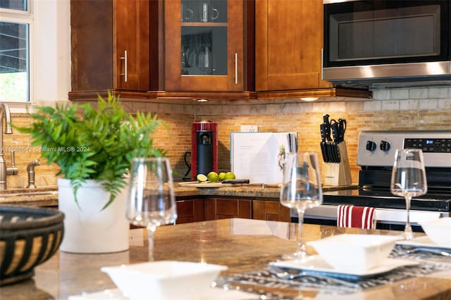 kitchen with stone counters, stove, and tasteful backsplash