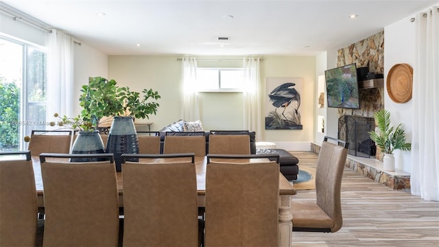 dining room with a stone fireplace and light hardwood / wood-style flooring